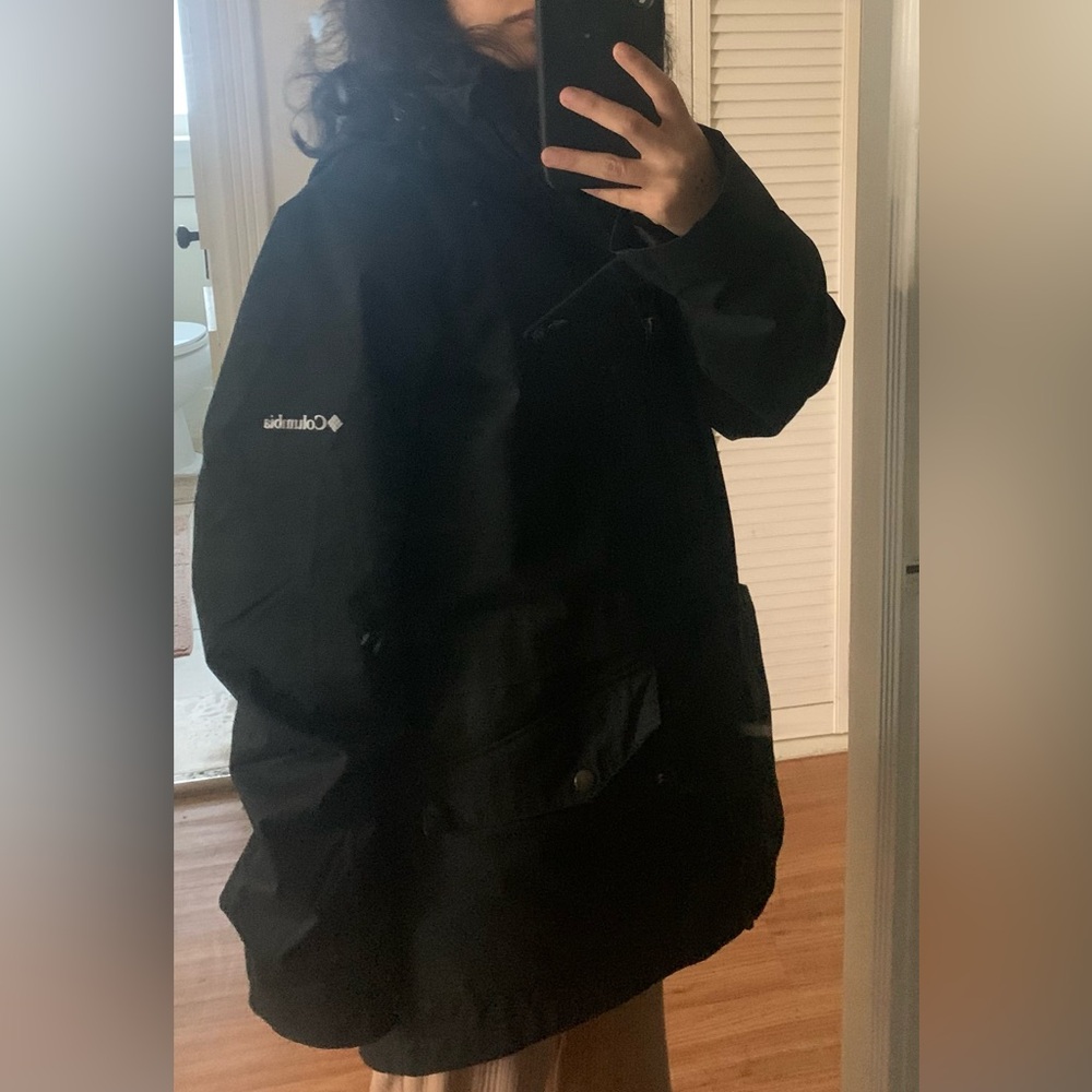 Selling Columbia black long jacket with hoodie, pockets, zipper, and buttons.